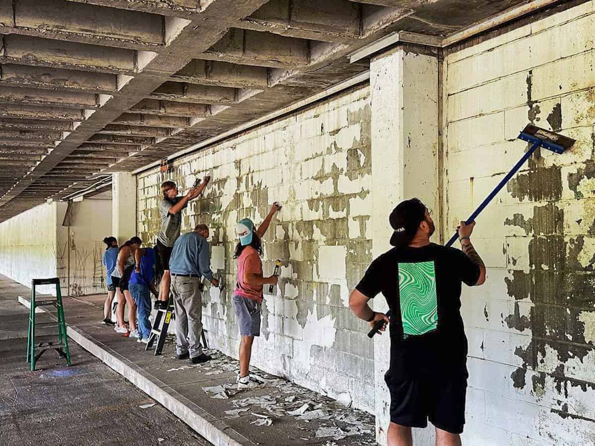 Volunteers from Grace Community Church in Fort Worth scrape off old paint in the parking garage